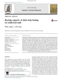 Bearing capacity of shell strip footing on reinforced sand